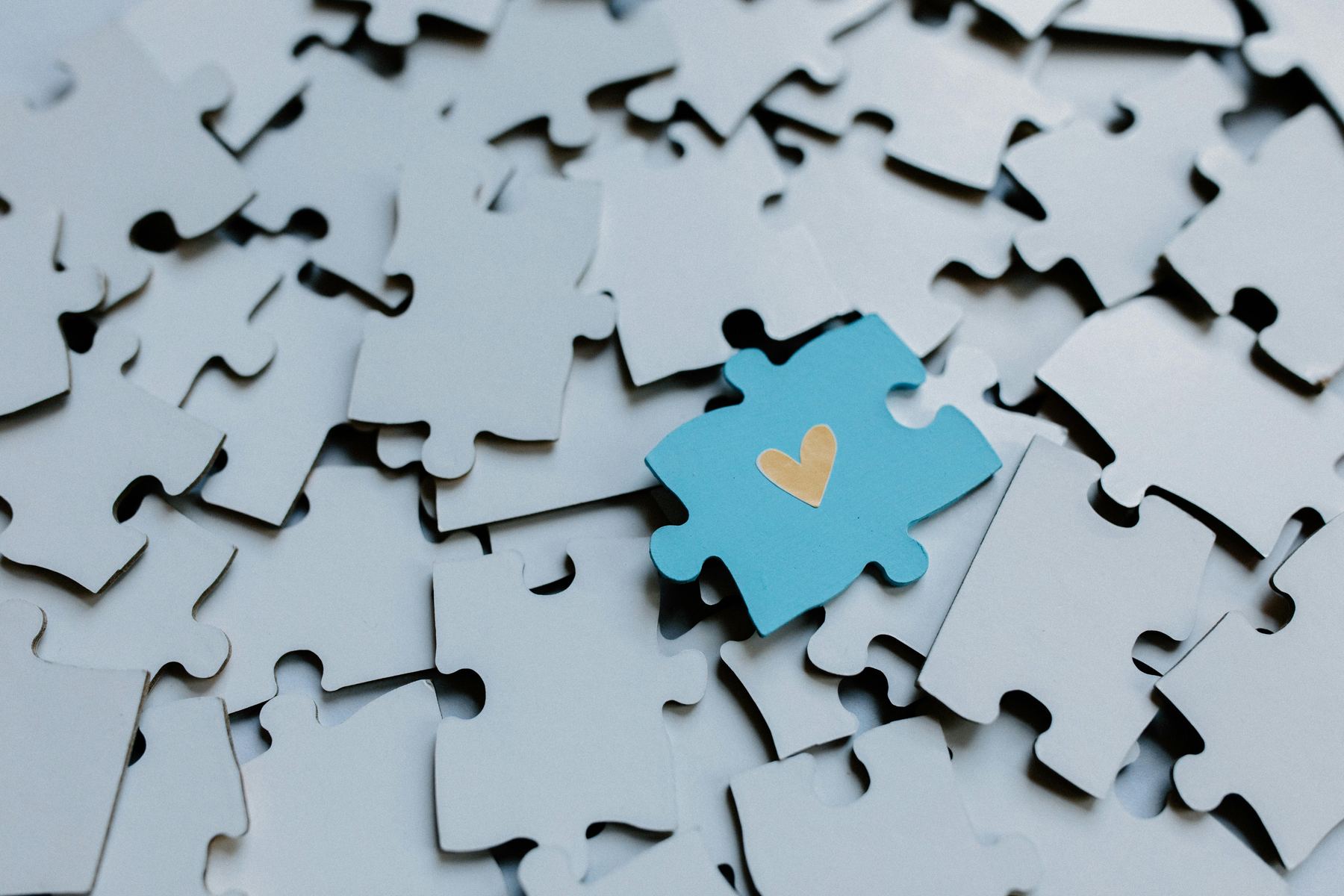 Une pièce de puzzle bleue ornée d'un cœur, au milieu des autres